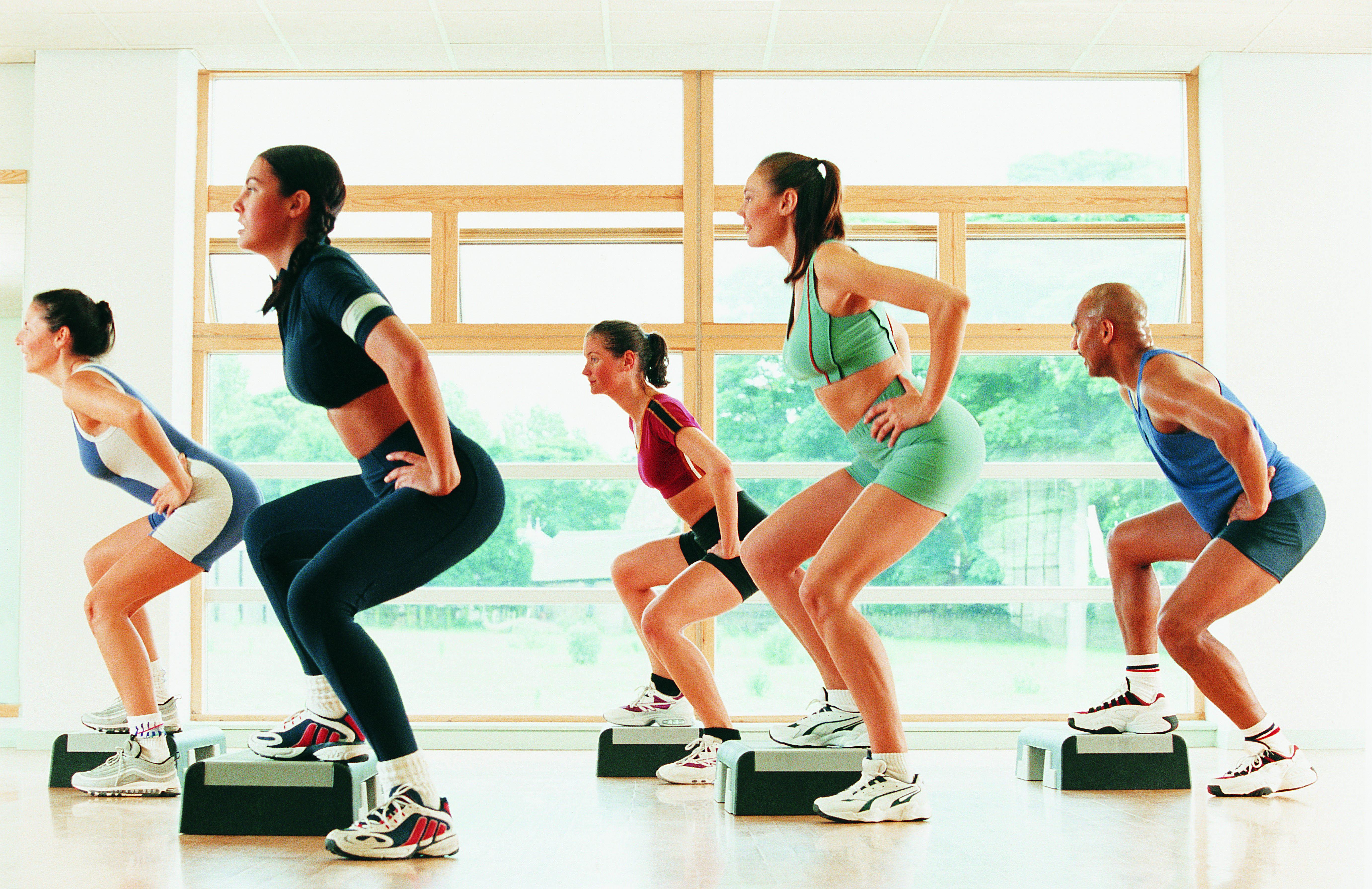 Three women in step workout class doing lateral lunges