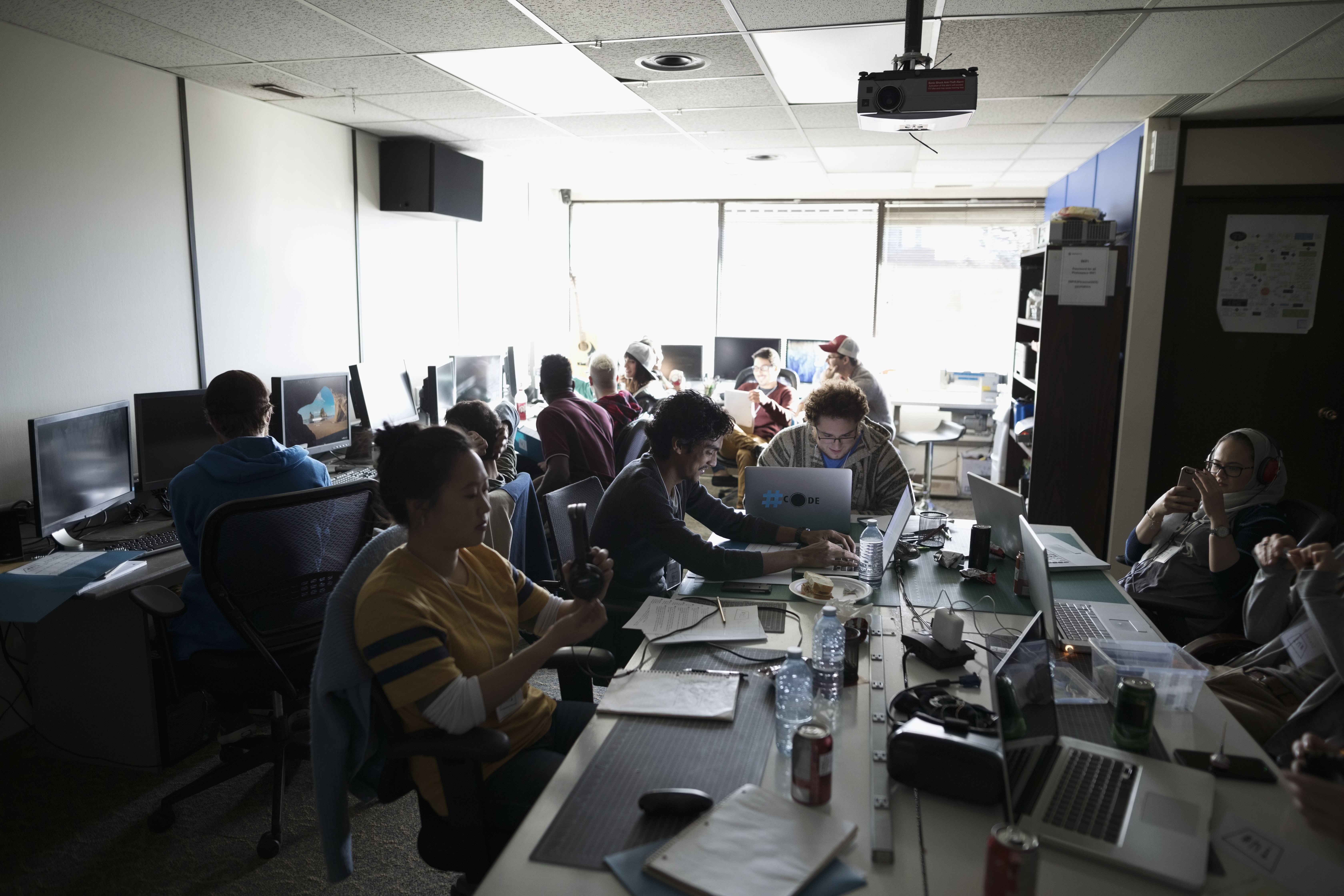 Hackers working hackathon at laptops and computers in dark office