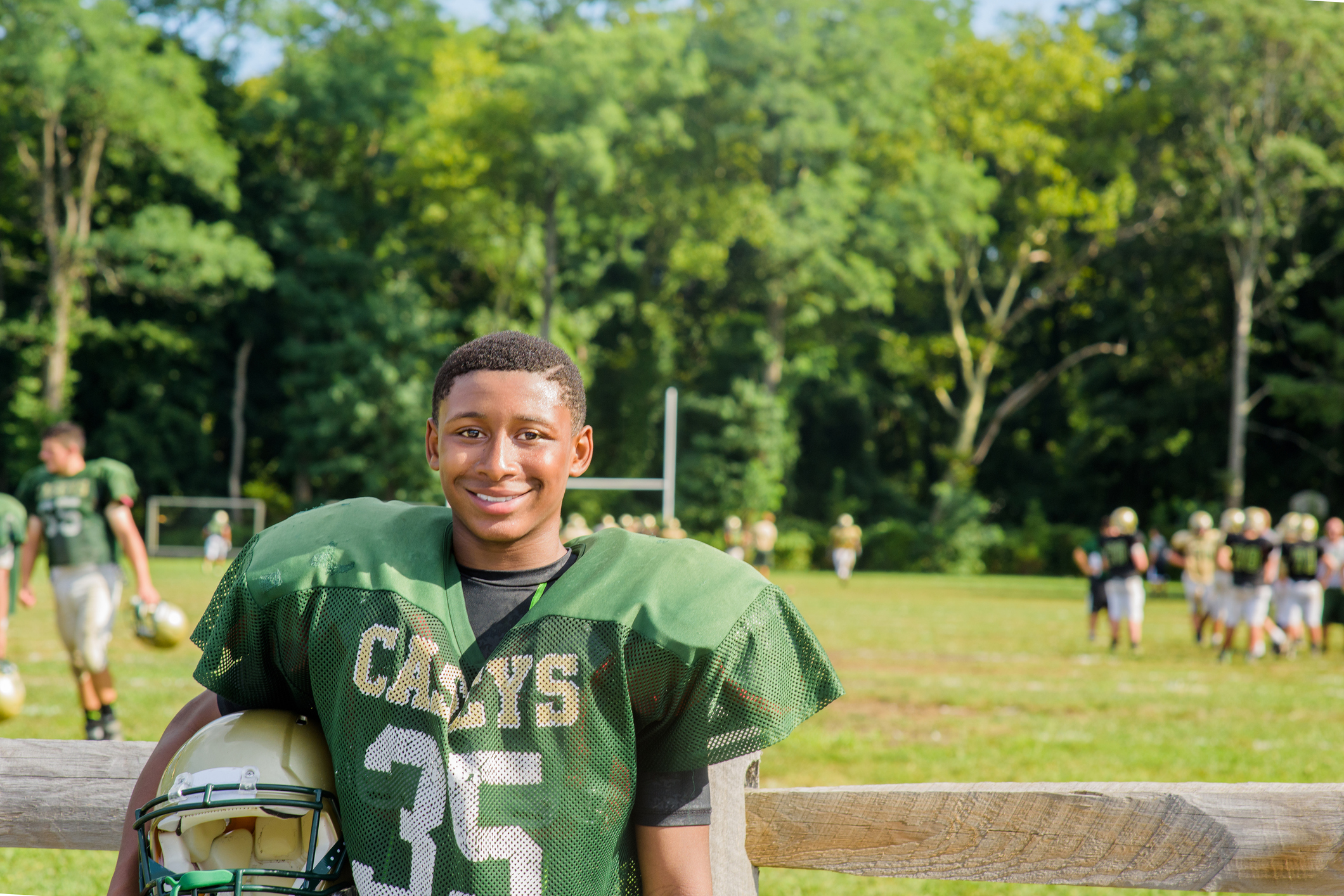 Portrait teenage male American football player holding helmet at playing field