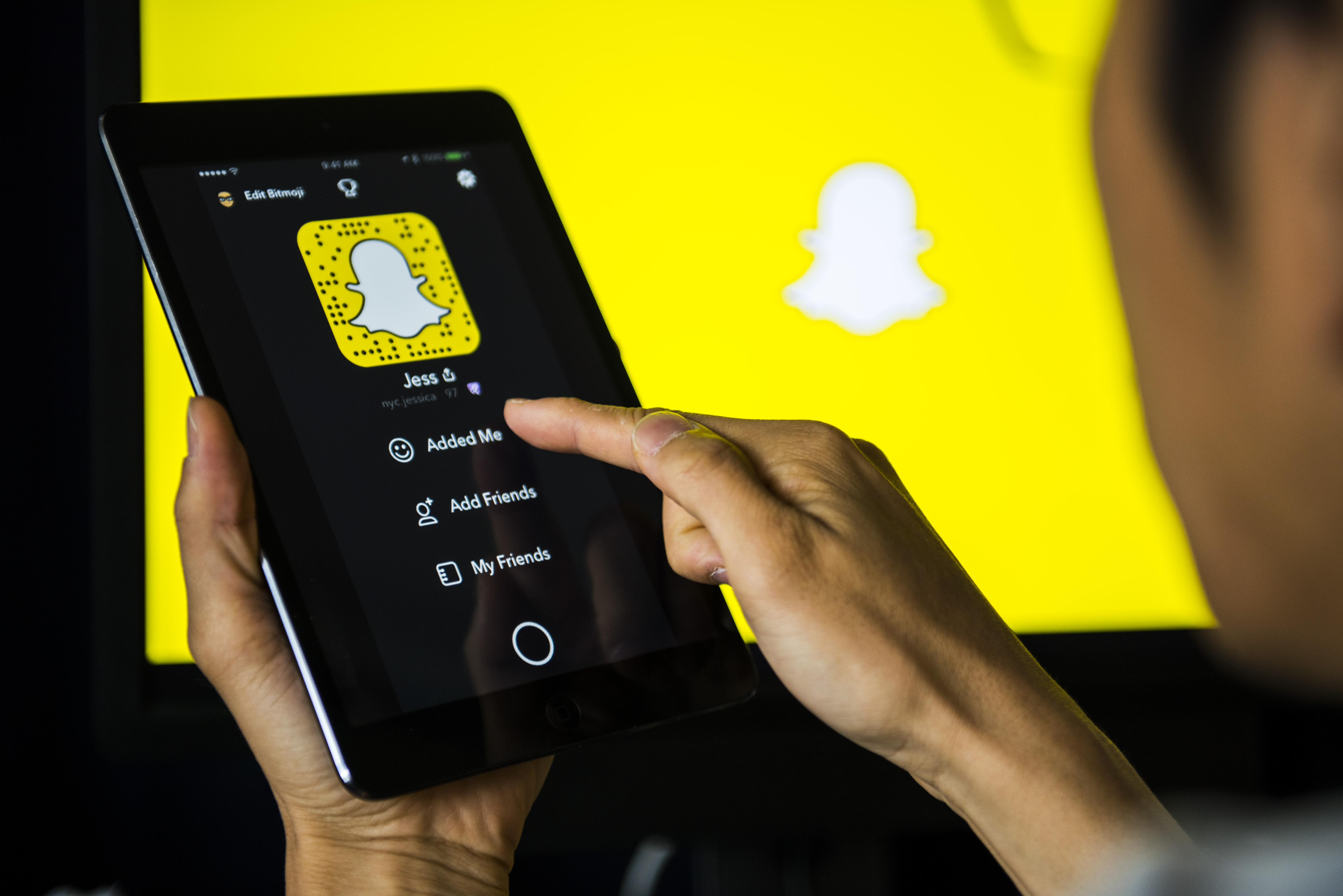 Young man holds a smart device while using SnapChat app
