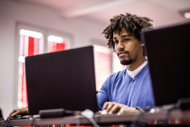 African American student studying on laptop at computer lab.