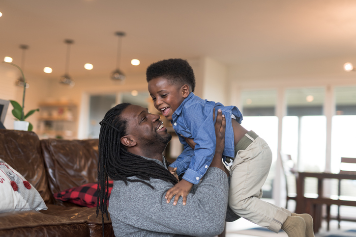 Young African American boy wrestling with dad